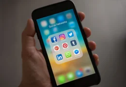 Person Holding Iphone Showing Social Networks Folder